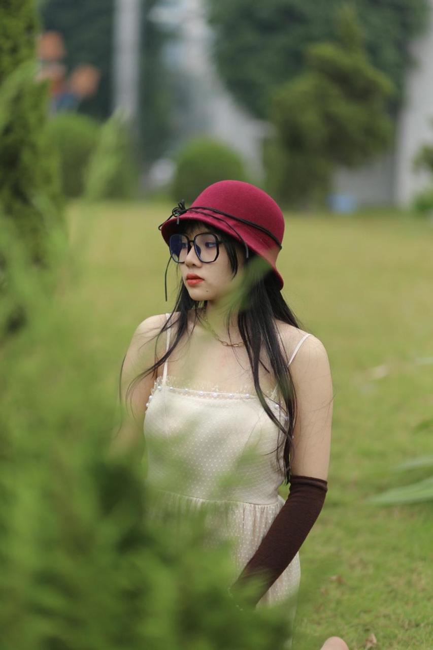 20P Pequena garota asiática com óculos e chapéu posando em seu vestido sexy de verão lá fora