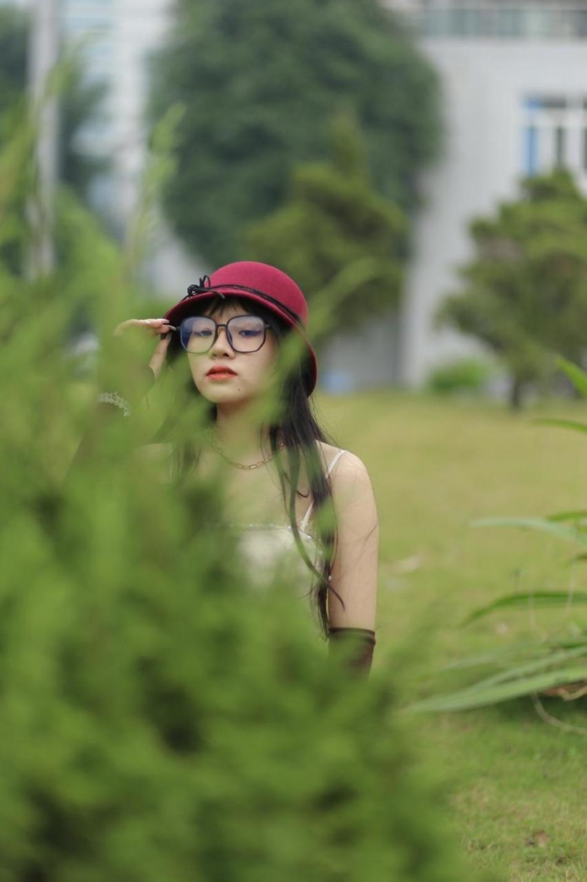20P Pequena garota asiática com óculos e chapéu posando em seu vestido sexy de verão lá fora