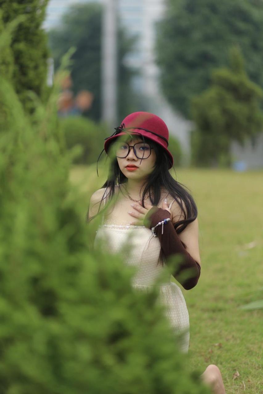 20P Pequena garota asiática com óculos e chapéu posando em seu vestido sexy de verão lá fora