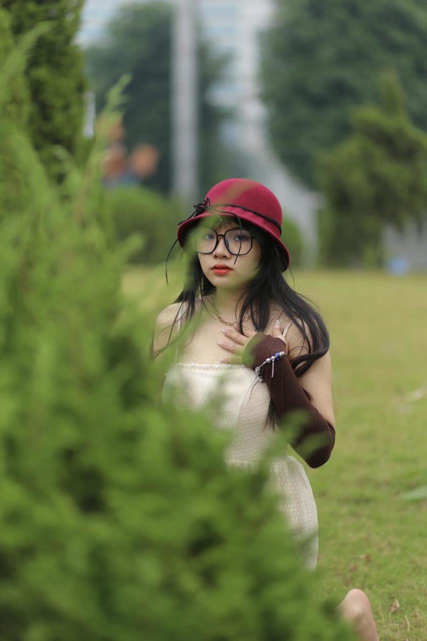 20P Pequena garota asiática com óculos e chapéu posando em seu vestido sexy de verão lá fora