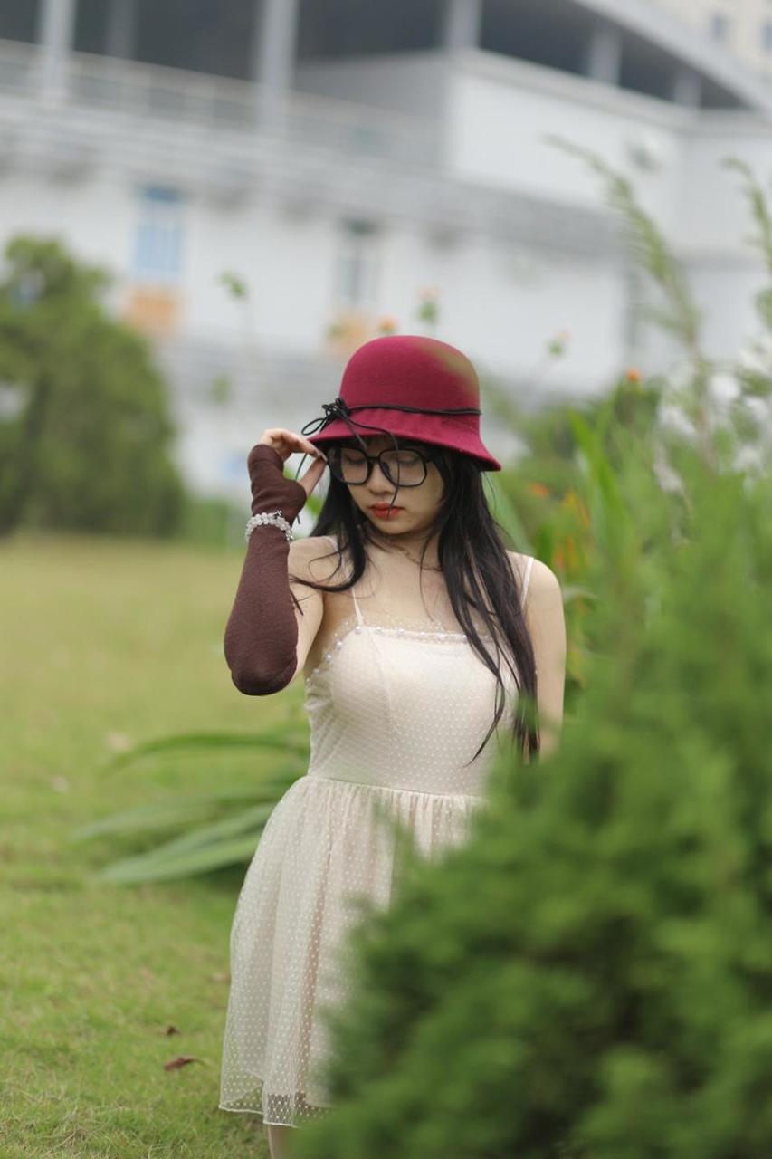 20P Pequena garota asiática com óculos e chapéu posando em seu vestido sexy de verão lá fora