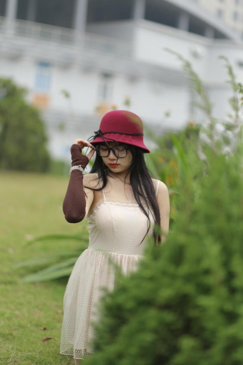 20P Pequena garota asiática com óculos e chapéu posando em seu vestido sexy de verão lá fora