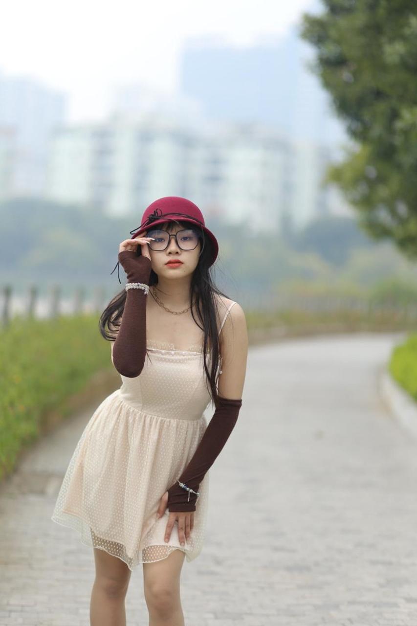 20P Pequena garota asiática com óculos e chapéu posando em seu vestido sexy de verão lá fora