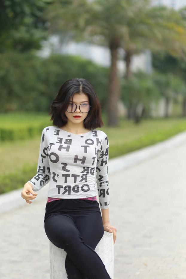 20P Pequena menina asiática com óculos posando de camisa branca e leggings quentes