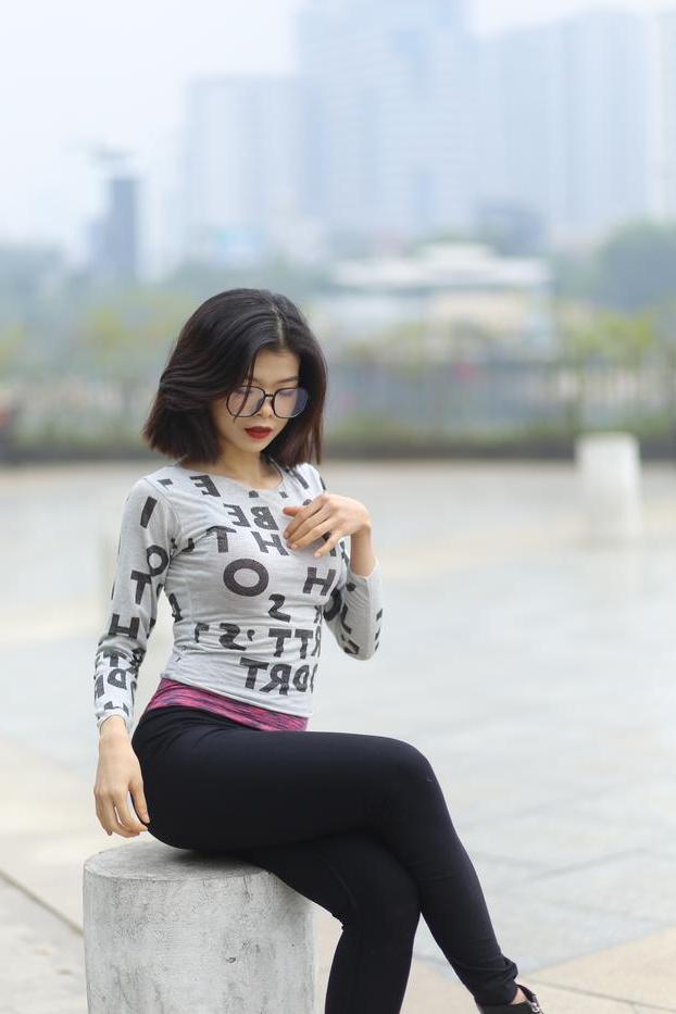 20P Pequena menina asiática com óculos posando de camisa branca e leggings quentes