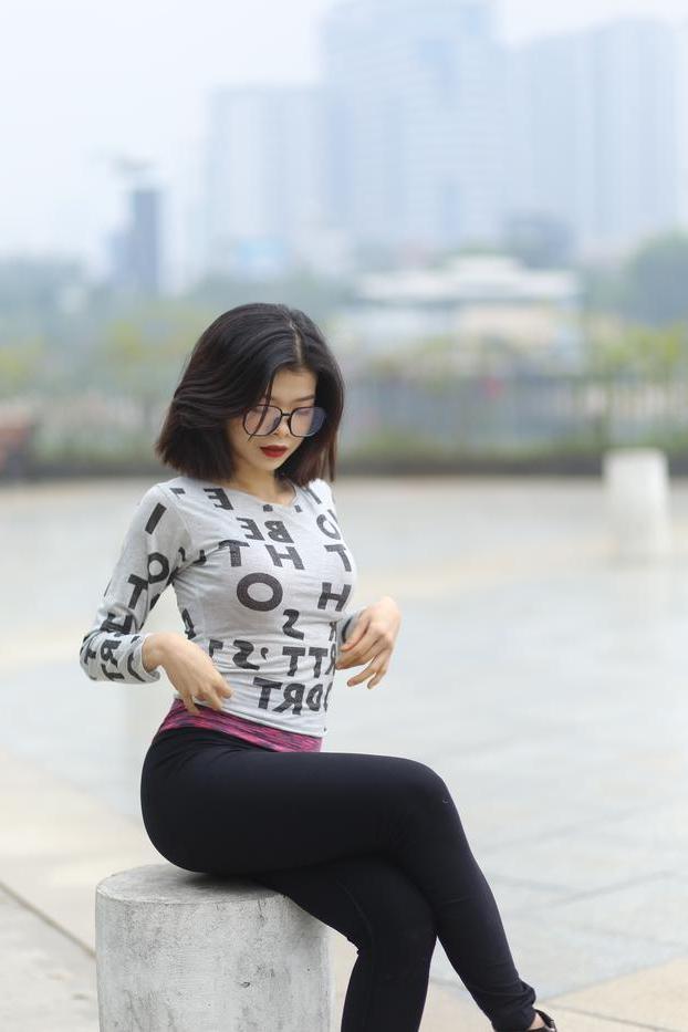 20P Pequena menina asiática com óculos posando de camisa branca e leggings quentes