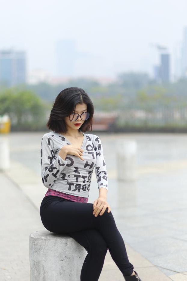 20P Pequena menina asiática com óculos posando de camisa branca e leggings quentes
