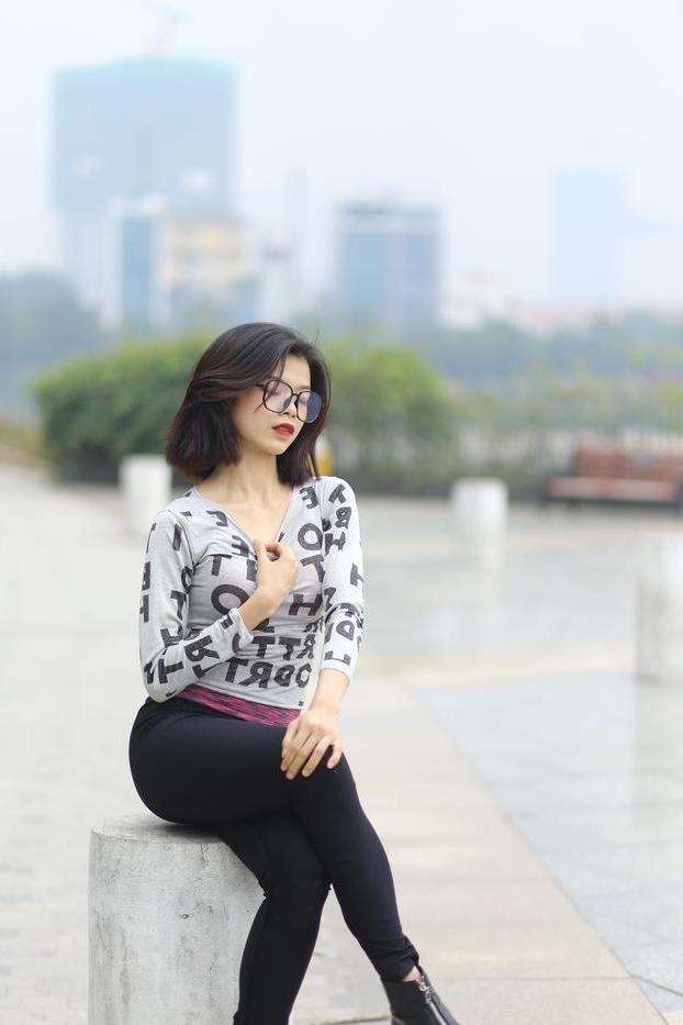 20P Pequena menina asiática com óculos posando de camisa branca e leggings quentes
