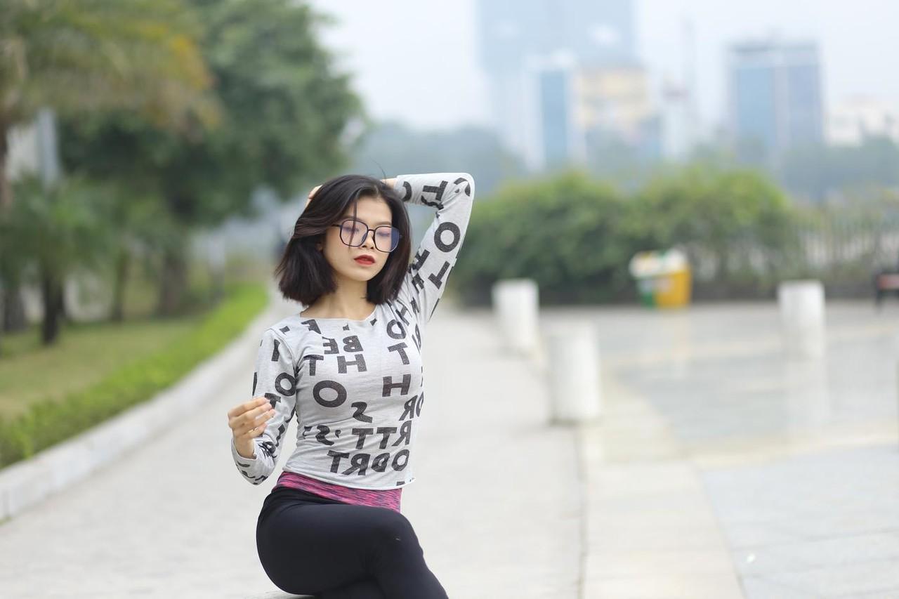 20P Pequena menina asiática com óculos posando de camisa branca e leggings quentes