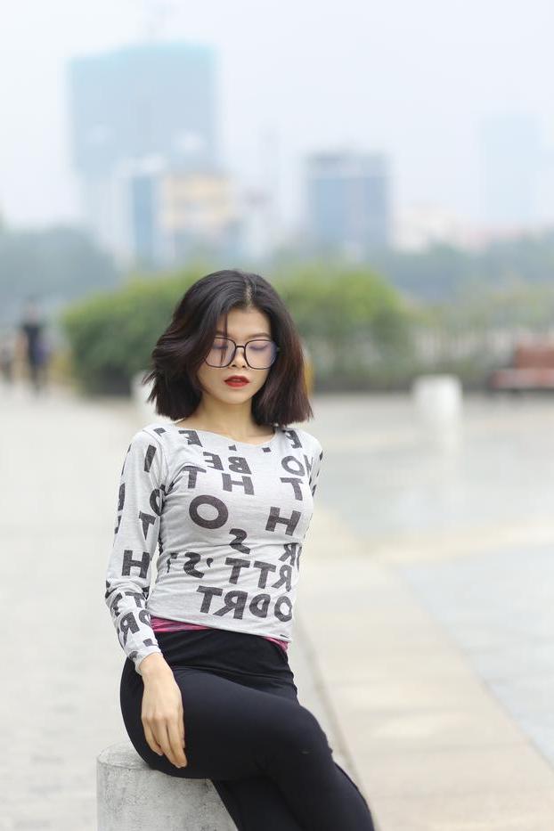 20P Pequena menina asiática com óculos posando de camisa branca e leggings quentes