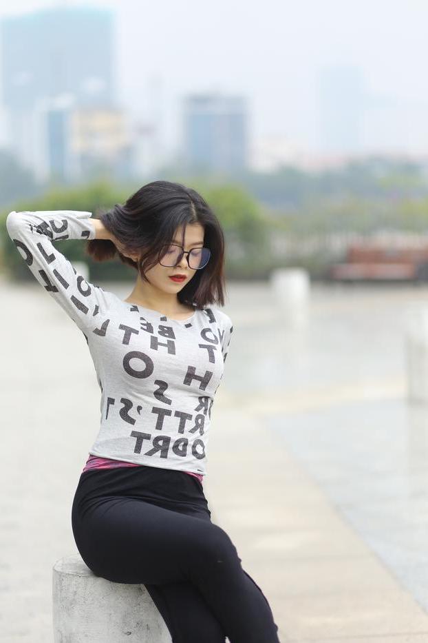20P Pequena menina asiática com óculos posando de camisa branca e leggings quentes