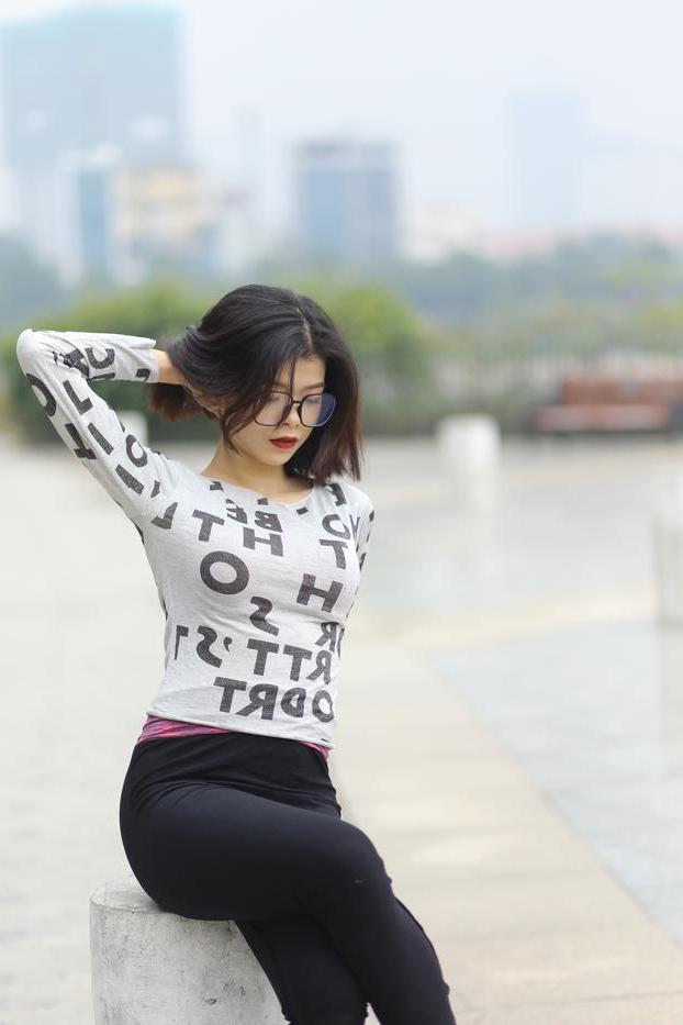 20P Pequena menina asiática com óculos posando de camisa branca e leggings quentes