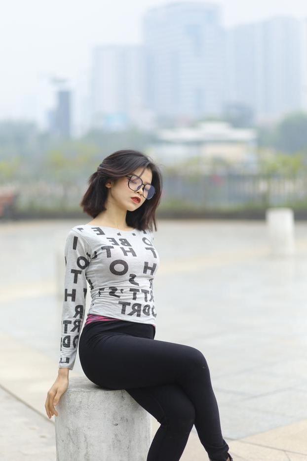 20P Pequena menina asiática com óculos posando de camisa branca e leggings quentes