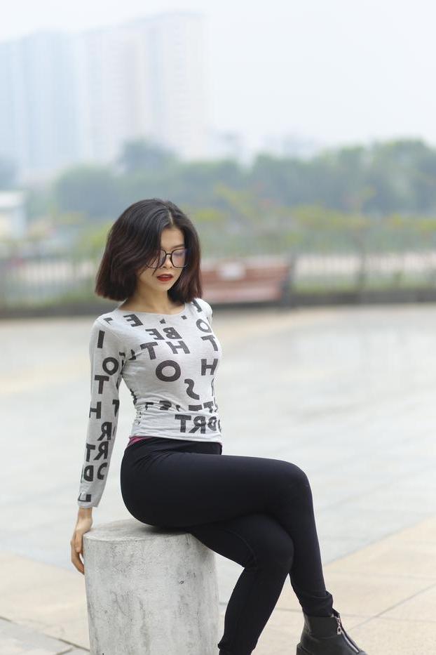 20P Pequena menina asiática com óculos posando de camisa branca e leggings quentes