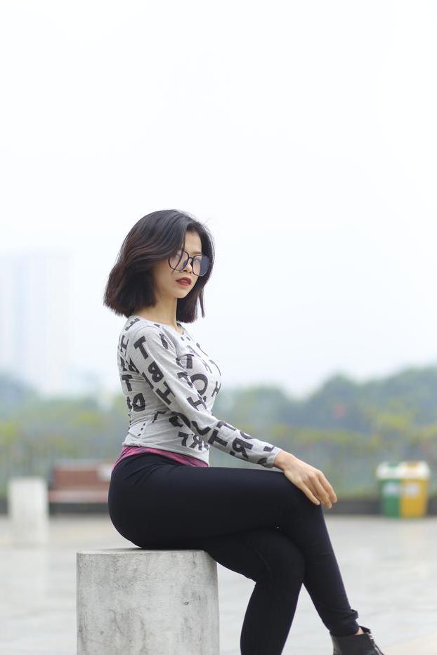 20P Pequena menina asiática com óculos posando de camisa branca e leggings quentes