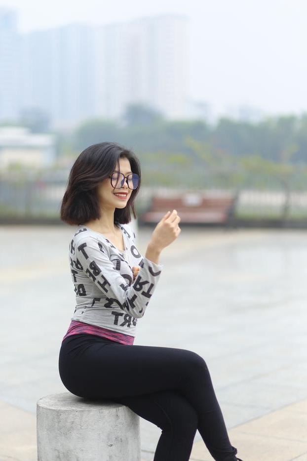 20P Pequena menina asiática com óculos posando de camisa branca e leggings quentes