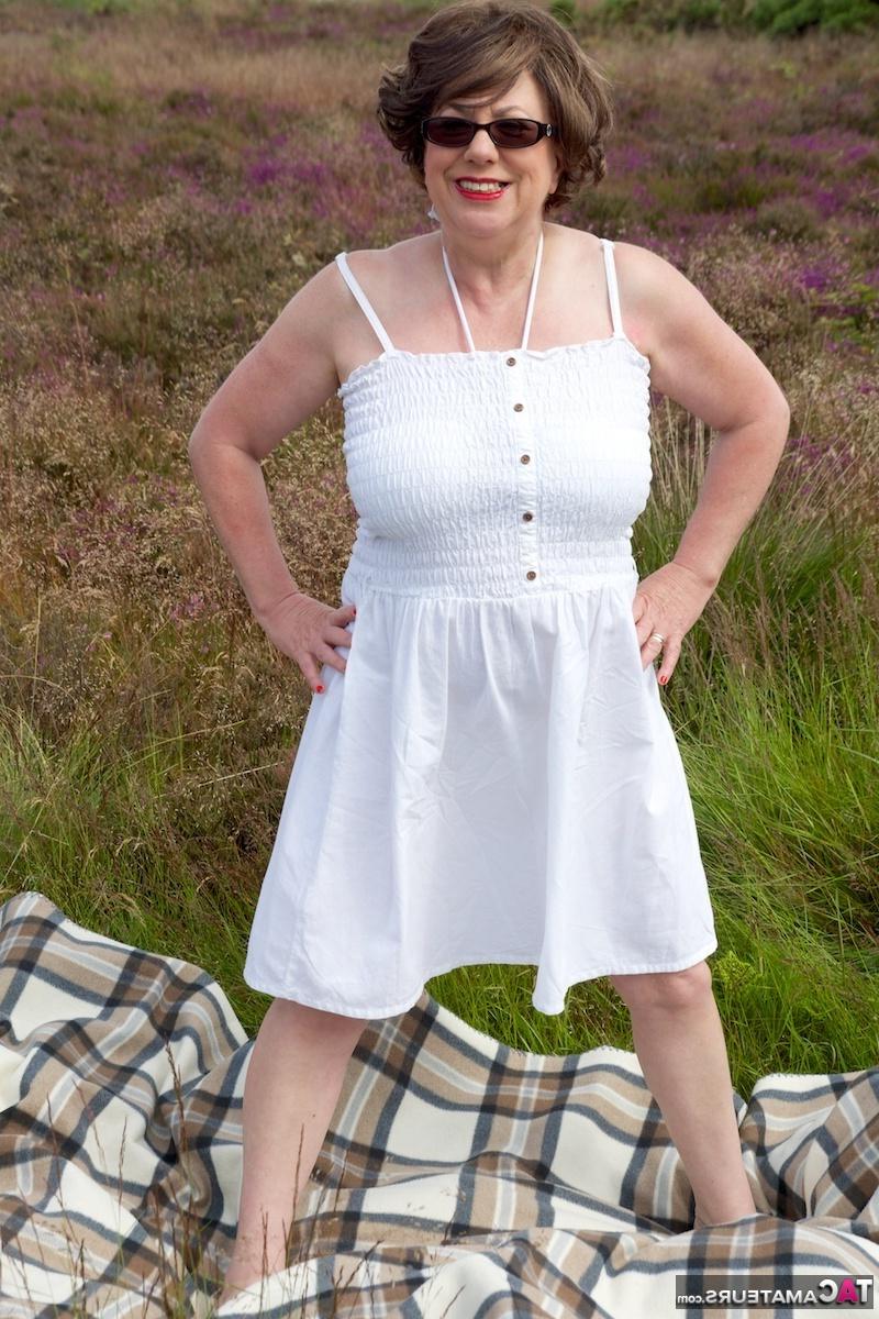 16P Dirty Doctor, une femme mûre, se met seins nus sur une couverture dans un champ.