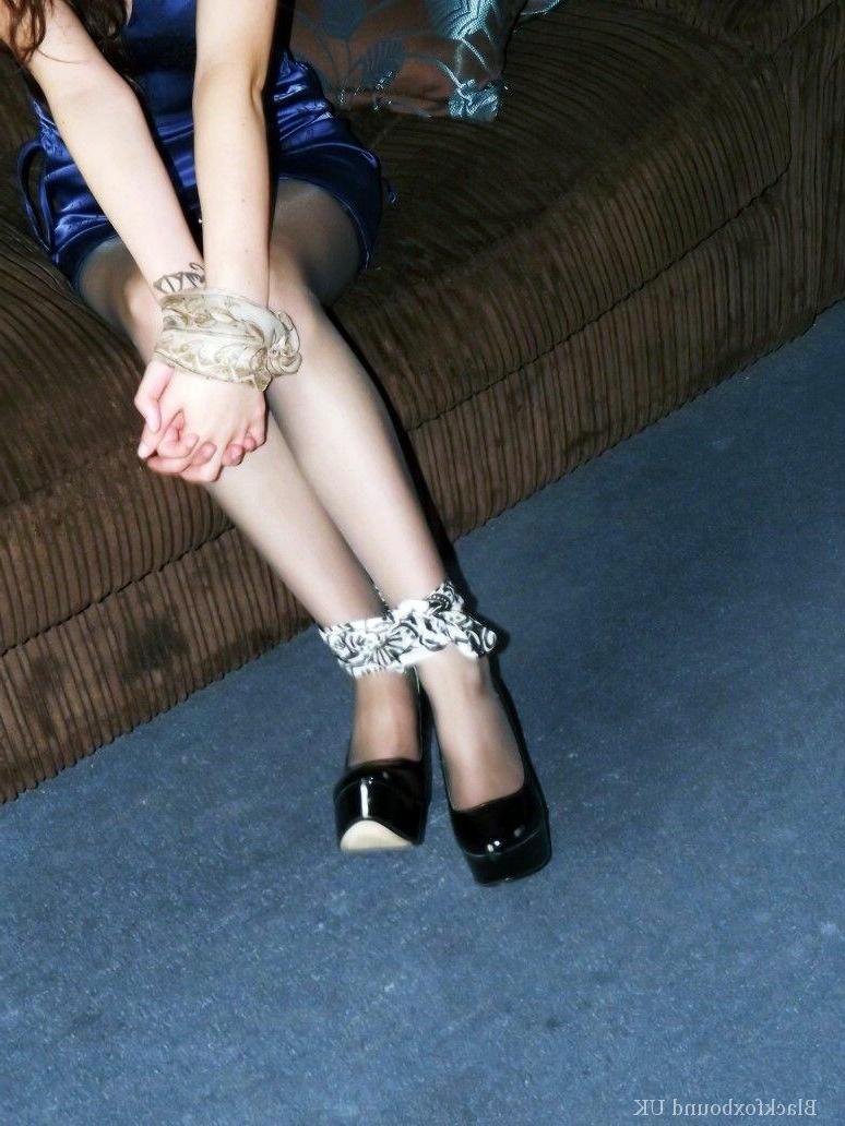 16P La chica vestida Tamara está atada por las muñecas y los tobillos mientras está en un sofá.