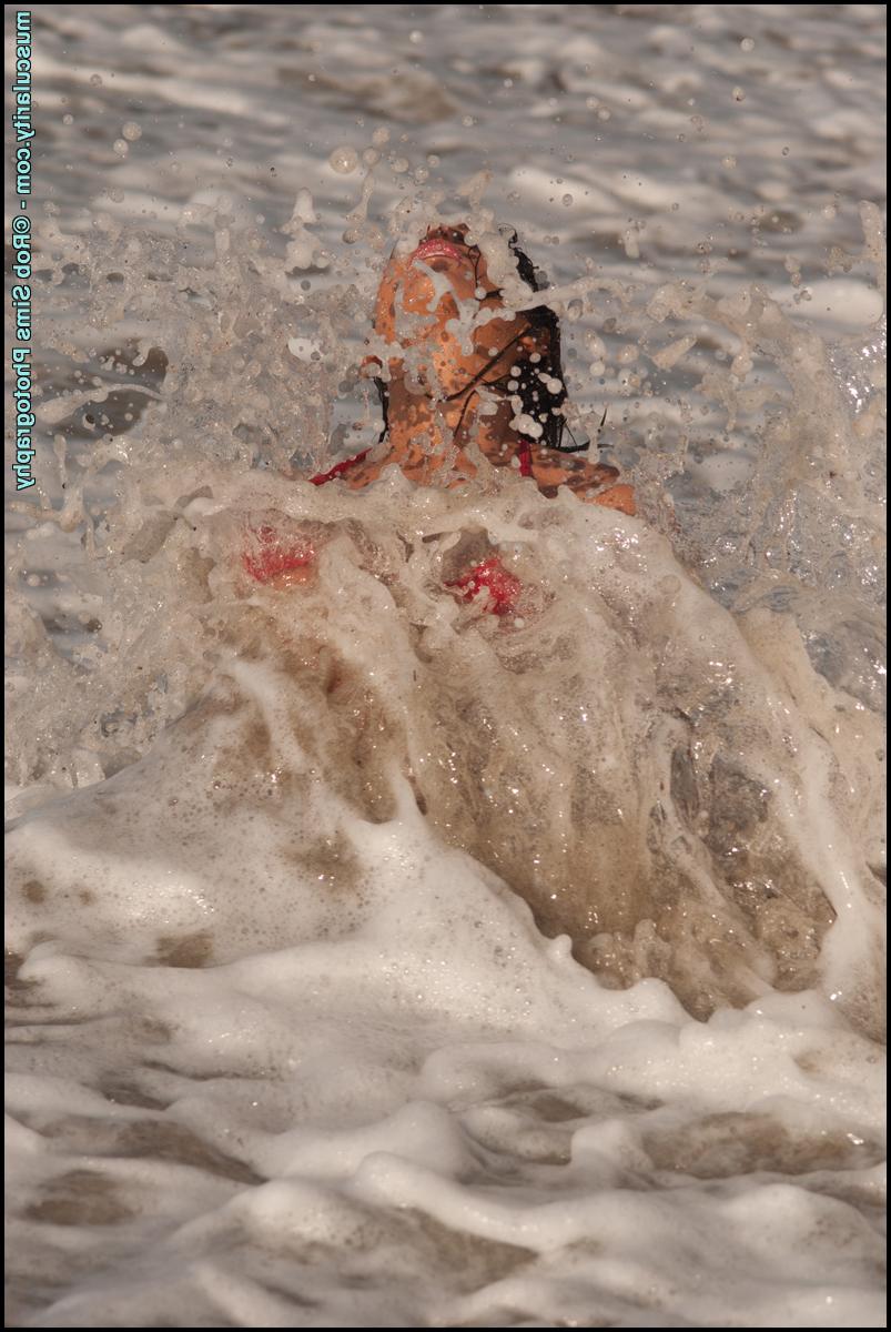 15P Fitness model Brenna Sims poses in a revealing red bikini in ocean surf