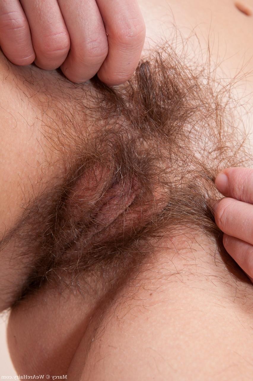 18P La adorable joven morena Marcy se desnuda en la cama y juega con su chocho peludo