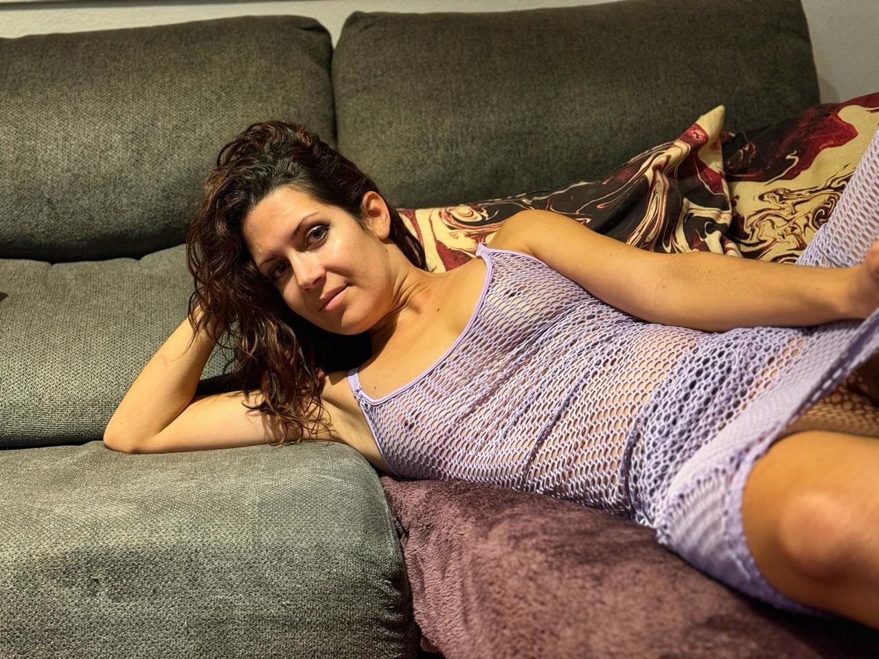 20P Beautiful brunette MILF teases in a see-through dress on the couch