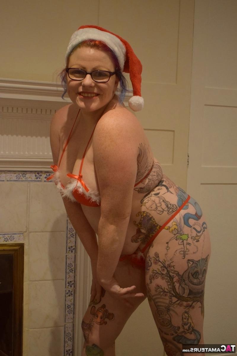16P Mulher mais velha tatuada descarta pose de biquíni nua com boné de Papai Noel