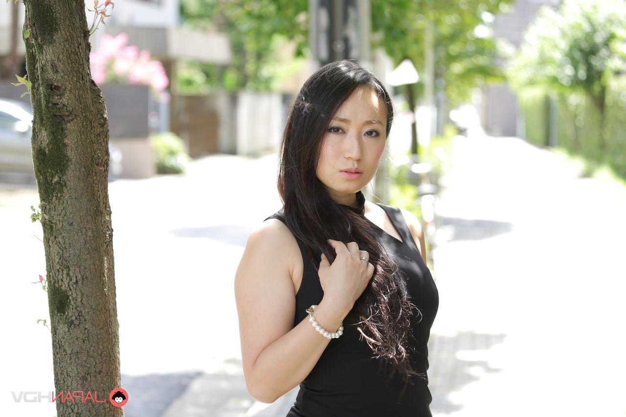 15P La beauté japonaise Aya Shiina est mannequin dans une rue de la ville dans une robe noire.