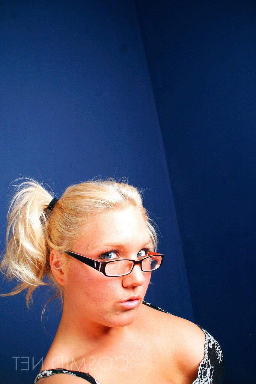 15P La jolie blonde Kay se déshabille en string tout en portant ses lunettes.