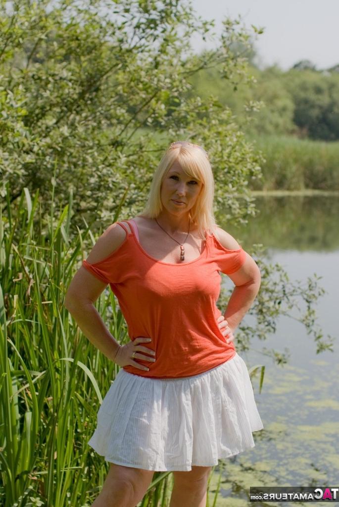 20P Melody, grosse femme blonde aux gros seins, se déshabille sur un quai au bord du lac.
