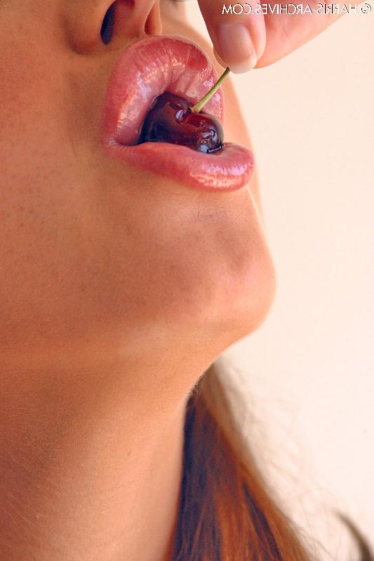 15P Das hübsche Mädchen Sandra Shine kräuselt ihre Zunge, während sie Saft aus einer Kirsche lutscht