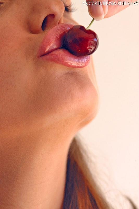15P Das hübsche Mädchen Sandra Shine kräuselt ihre Zunge, während sie Saft aus einer Kirsche lutscht