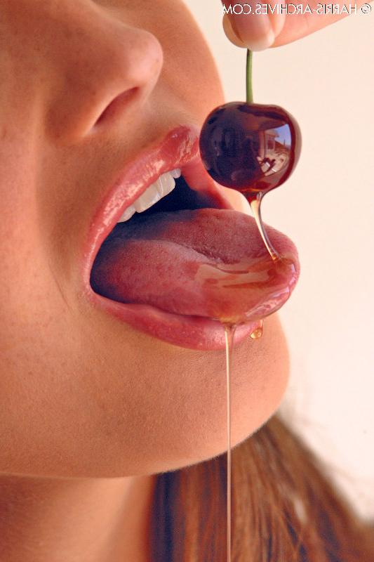 15P Das hübsche Mädchen Sandra Shine kräuselt ihre Zunge, während sie Saft aus einer Kirsche lutscht