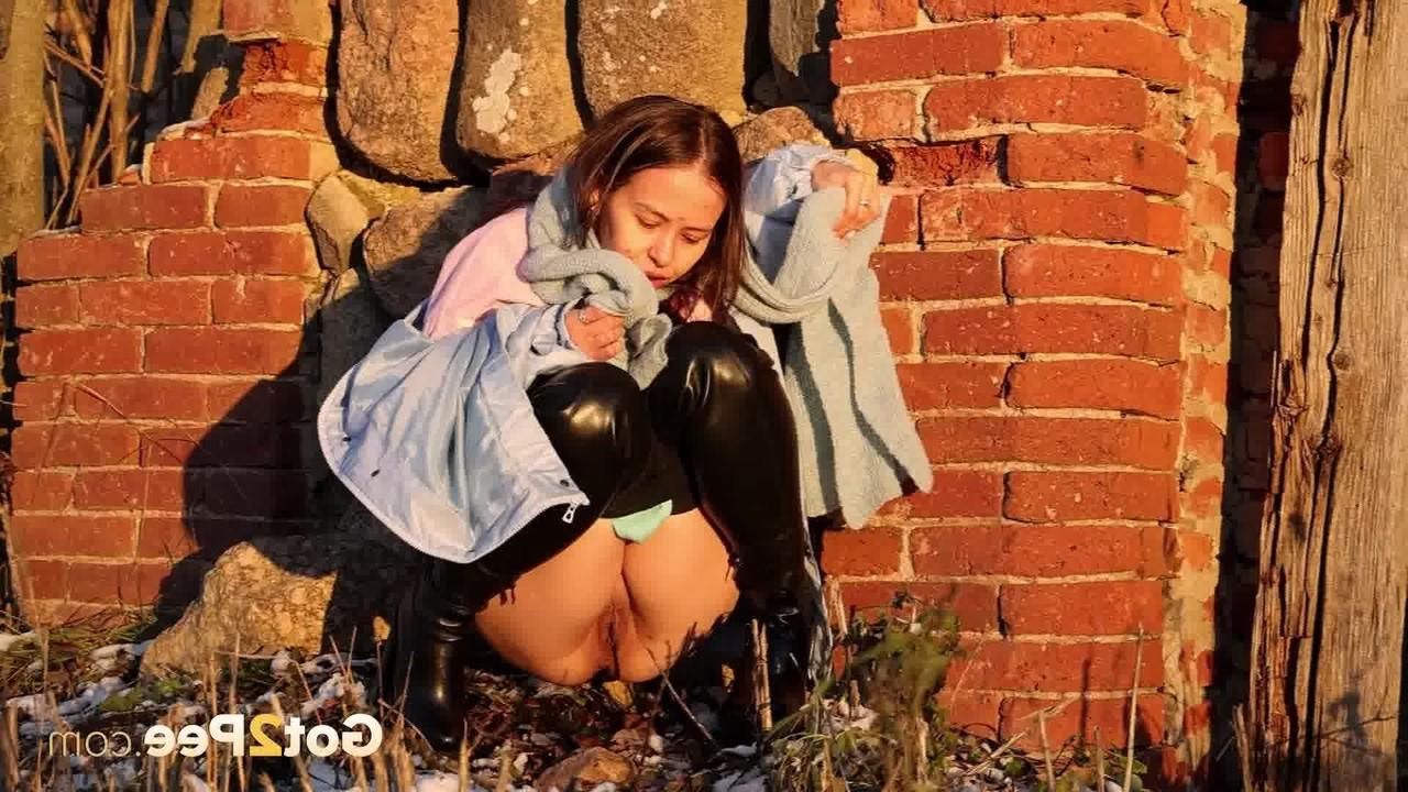 15P Pinkycat, une asiatique, s'accroupit pour pisser sur un sol gelé près d'un mur de briques.