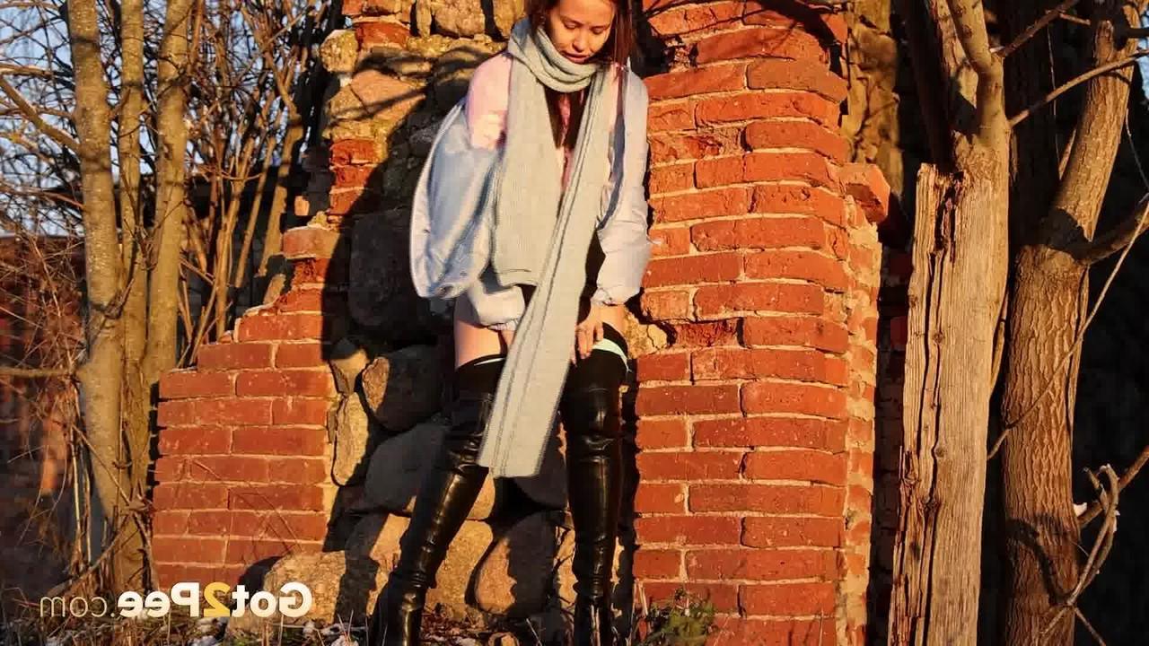 15P Pinkycat, une asiatique, s'accroupit pour pisser sur un sol gelé près d'un mur de briques.