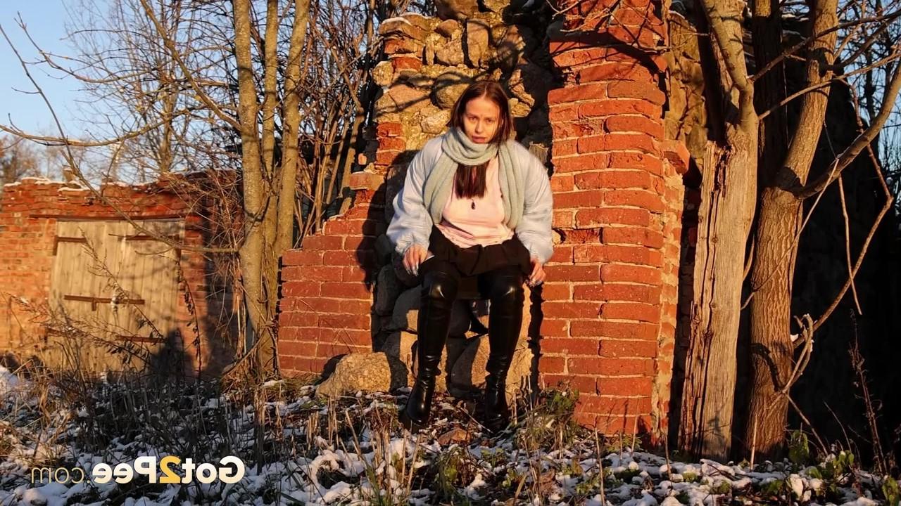 15P Pinkycat, une asiatique, s'accroupit pour pisser sur un sol gelé près d'un mur de briques.