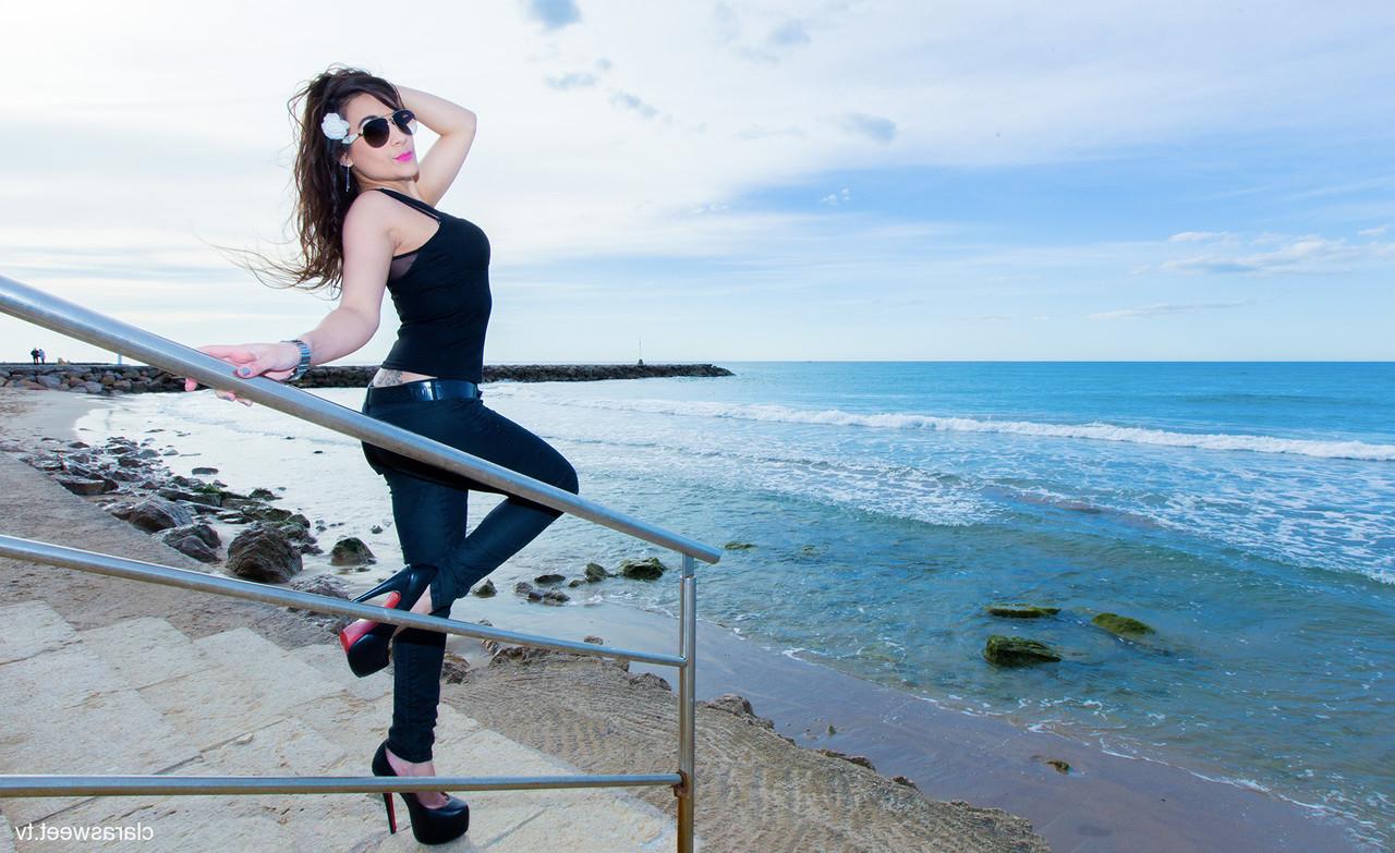 15P A modelo totalmente natural Clara Sweet posando na praia com sua roupa sexy e salto alto