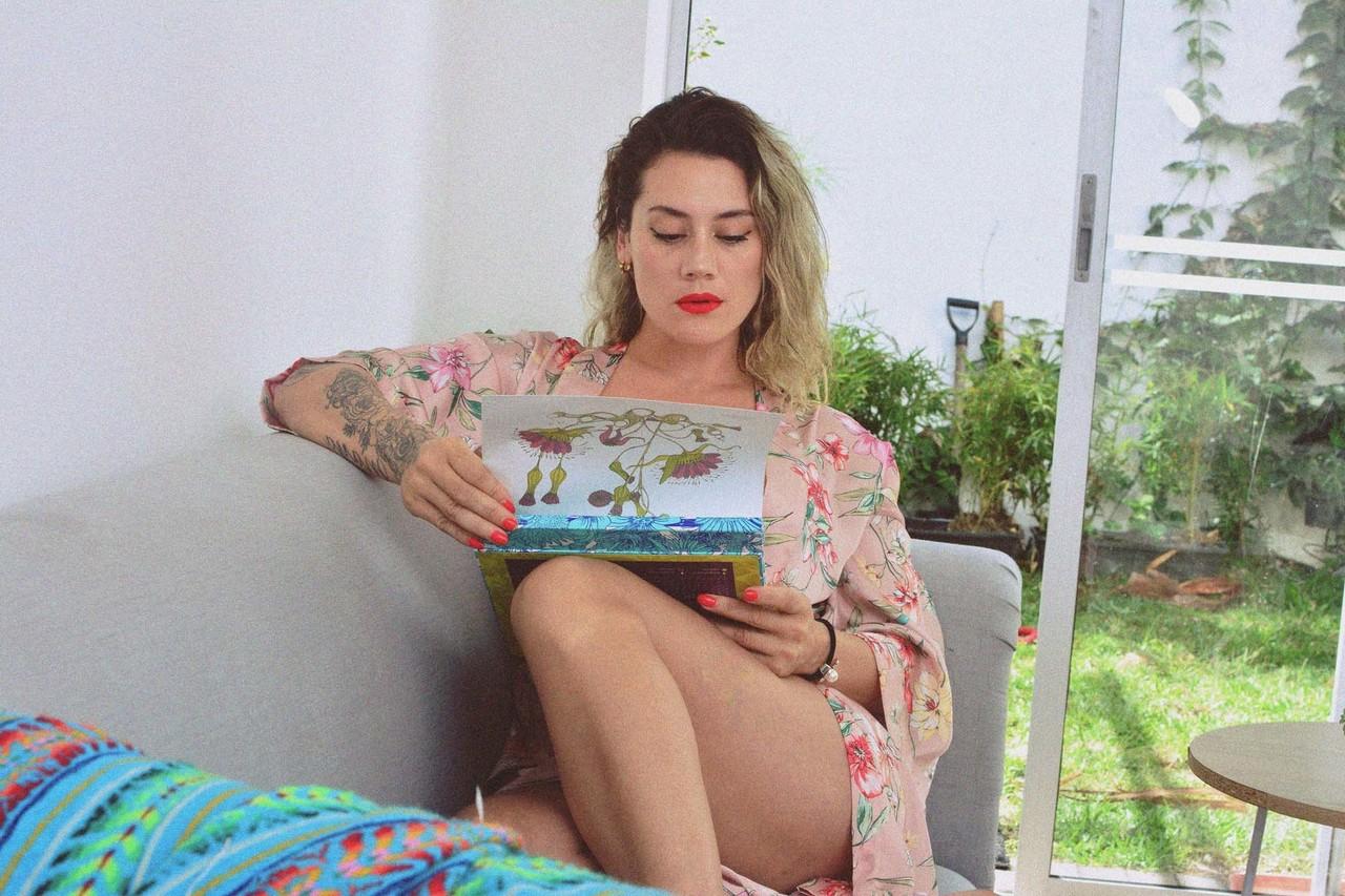 15P La MILF encrée Andrea Garcia expose ses incroyables gros seins en lisant sur un canapé.