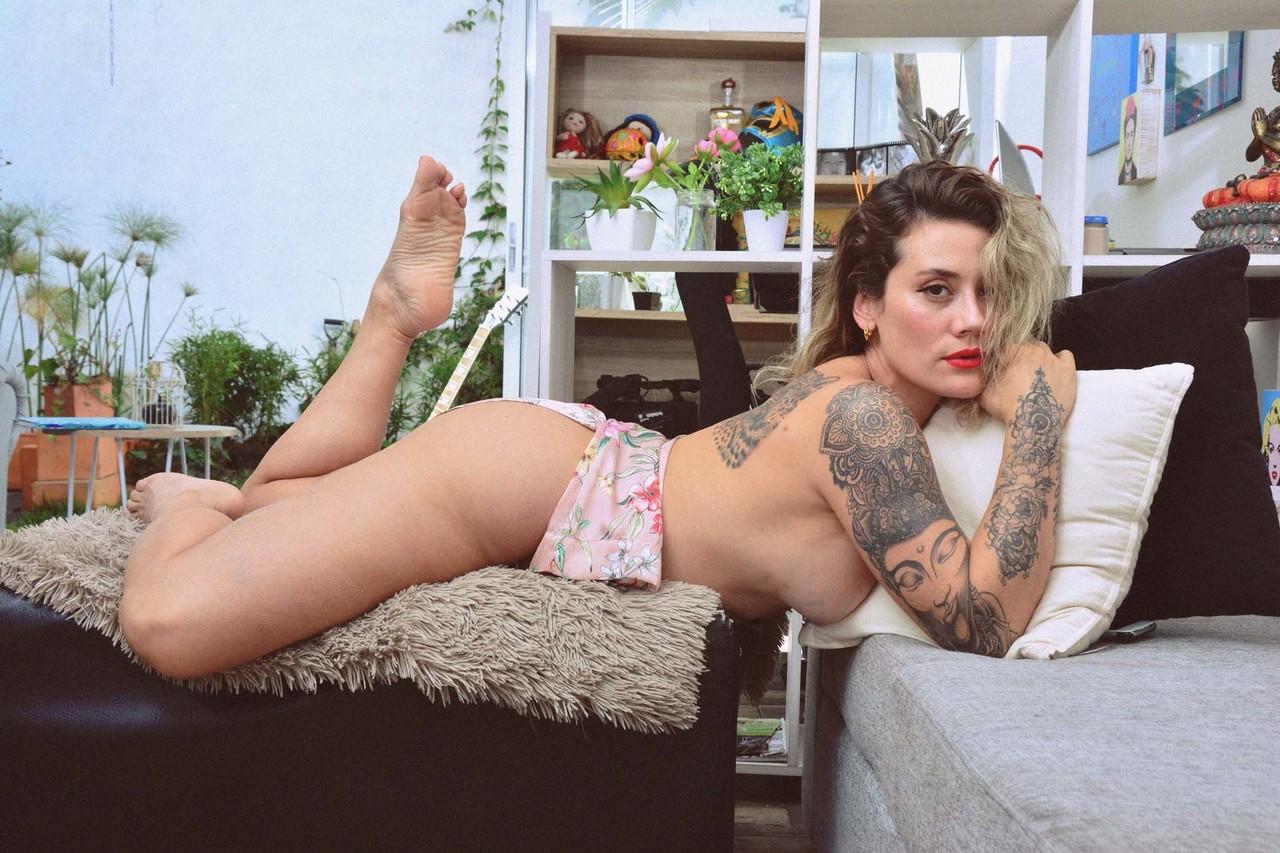 15P La MILF encrée Andrea Garcia expose ses incroyables gros seins en lisant sur un canapé.