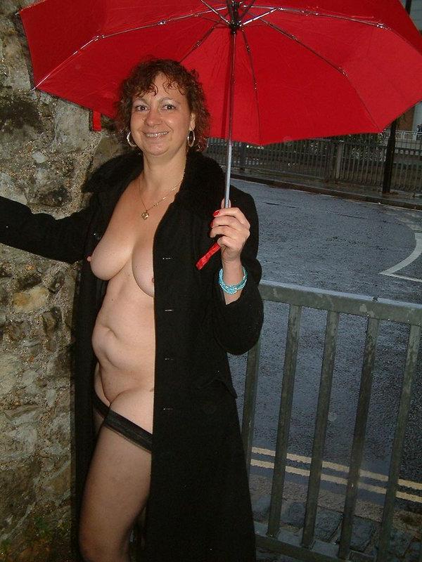 12P Mulher britânica madura segura um guarda-chuva enquanto fica nua em público