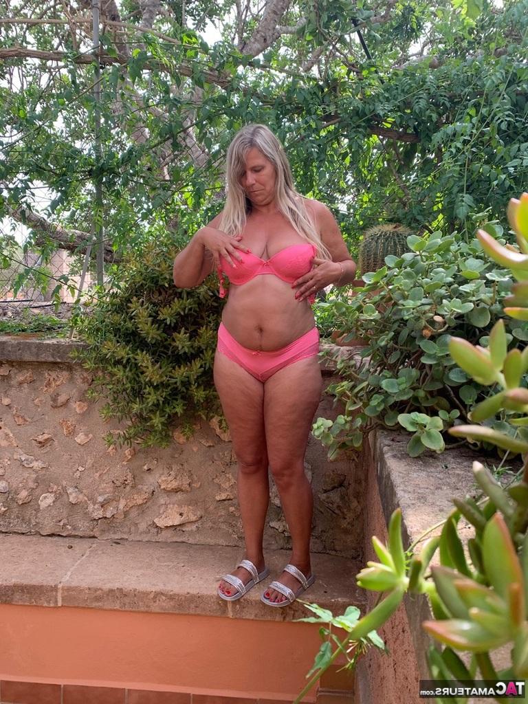 20P La blonde plus âgée Sweet Susi enlève son soutien-gorge et sa culotte roses pour se mettre nue dans le jardin.