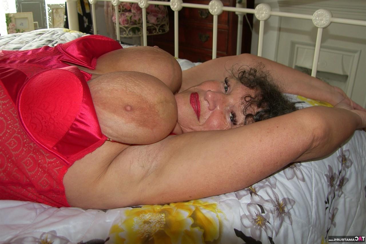16P Une grosse mature montre ses gros seins sur un lit de repos avec des cuissardes.