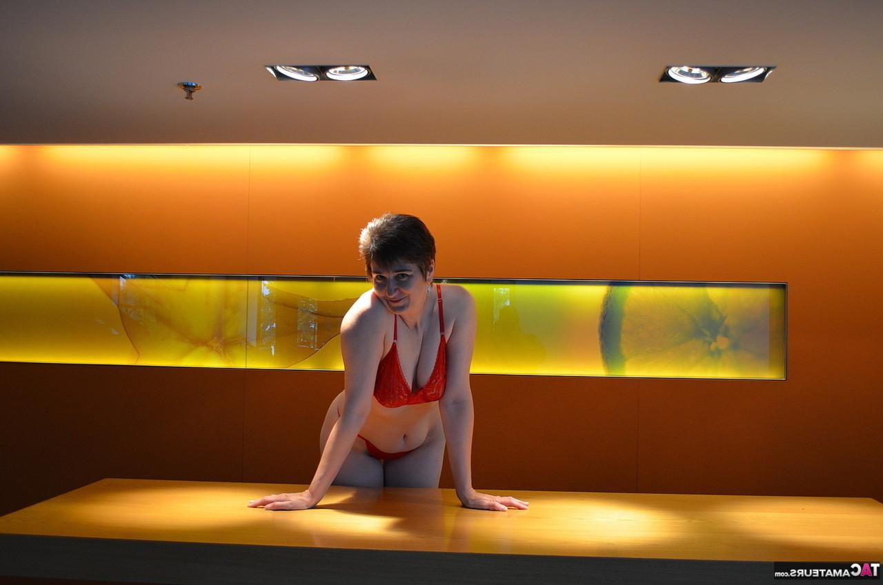 16P Hotmilf, une femme mûre, se déshabille en portant une paire de bottes rouges.