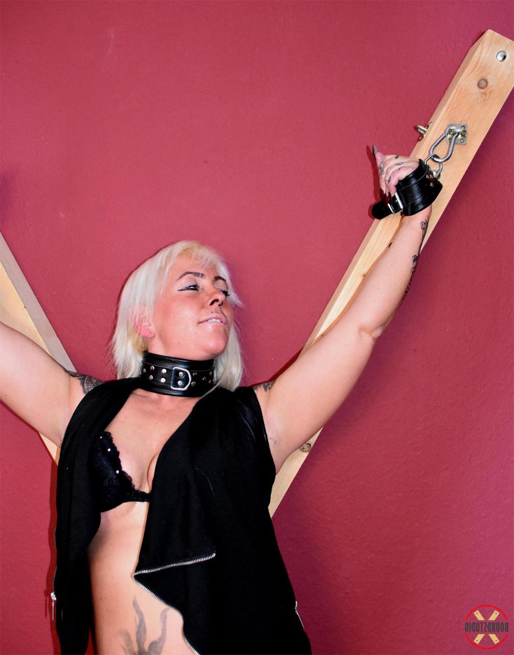 16P Collared blonde Hanka is affixed to a St Andrews Cross in black leather boots