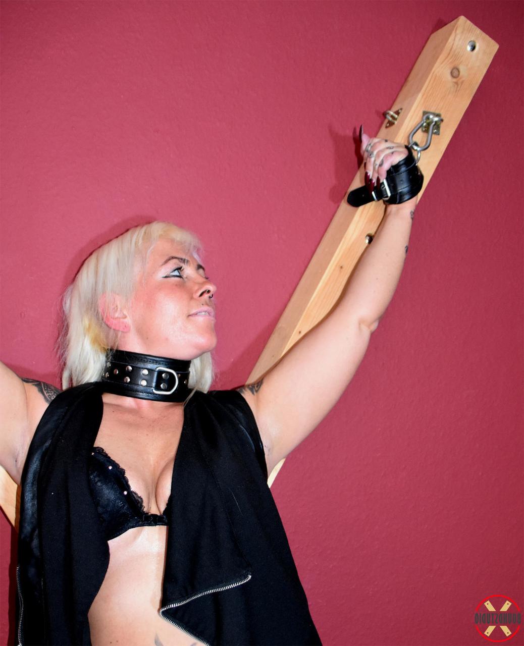16P Collared blonde Hanka is affixed to a St Andrews Cross in black leather boots