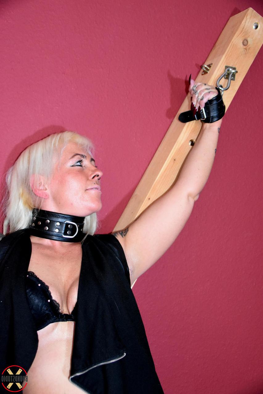 16P Collared blonde Hanka is affixed to a St Andrews Cross in black leather boots