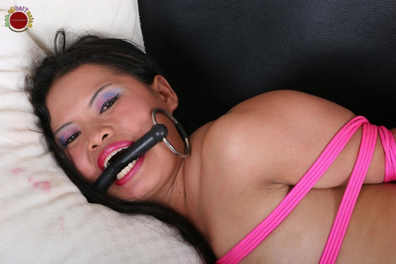16P Une jolie esclave asiatique fait du sport un peu dans sa bouche alors qu'elle est attachée avec une corde rose.