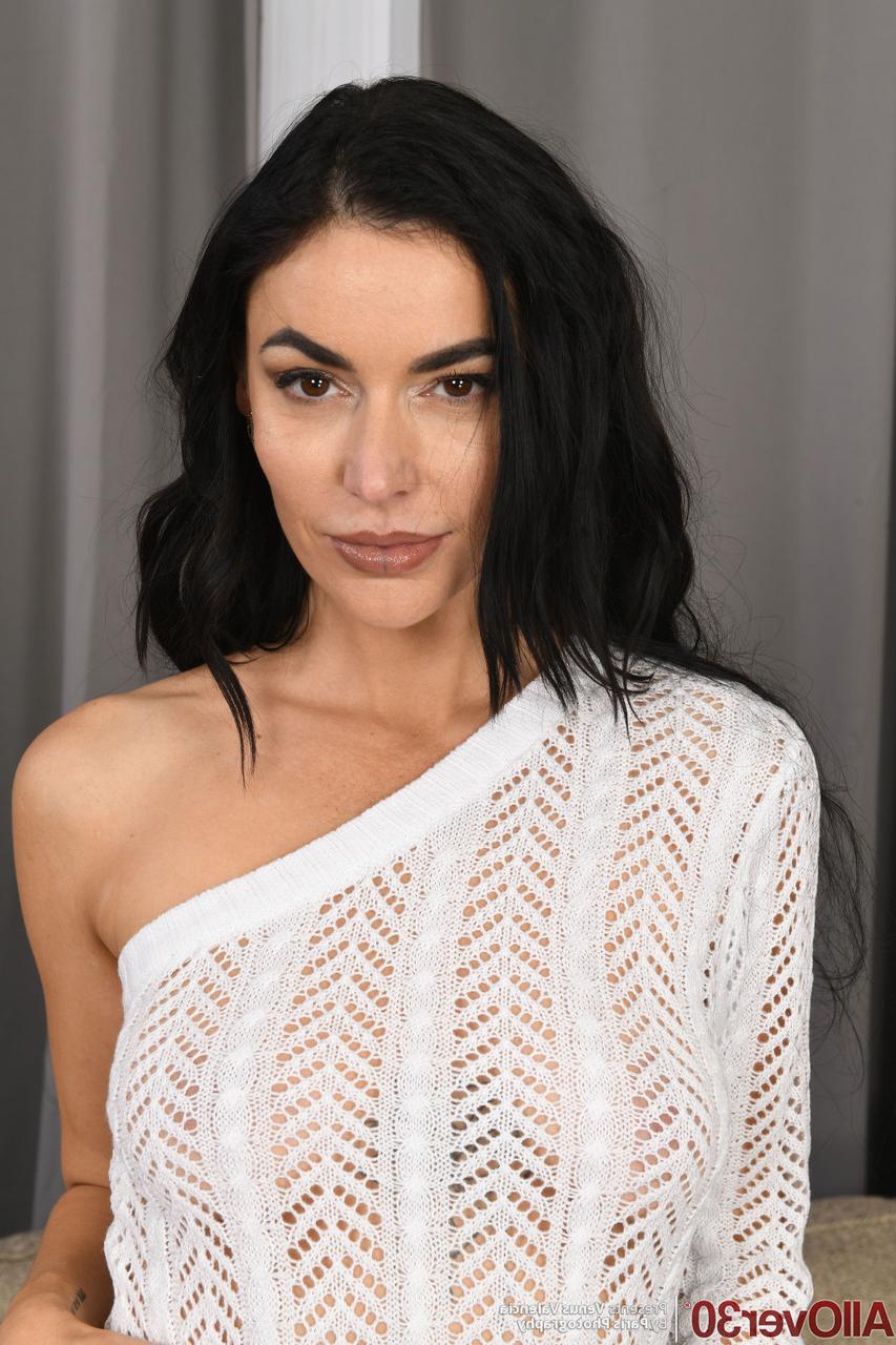 16P La MILF brune Venus Valencia se doigte la chatte après s'être nue sur un canapé.