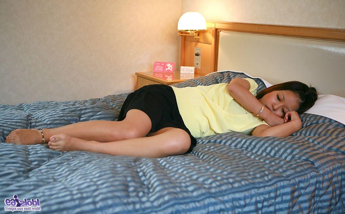 16P Une jolie fille japonaise se fait caresser les petits seins sur un lit d'hôtel