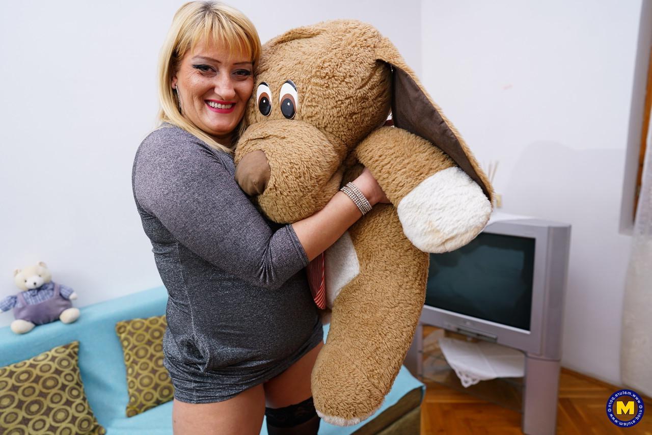 16P Une blonde plus âgée et pulpeuse se met nue sur un canapé avec un porte-jarretelles et des bas.