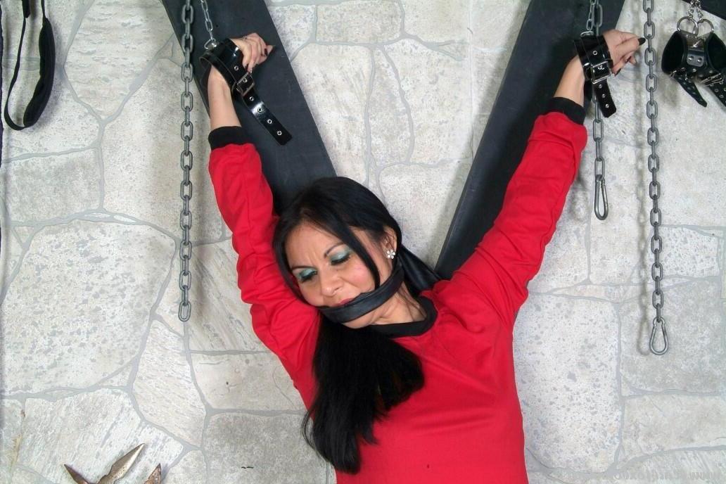 16P Dunkelhaariges Mädchen ist vollständig bekleidet an einem Andreaskreuz befestigt